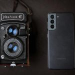 A vintage Yashica camera next to a modern smartphone, showcasing old and new technology.