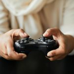 Close-up of a person holding a video game controller, focusing on hand interaction.